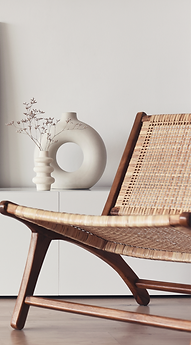 Interior styling detail with woven chair, sculptural ceramic vase, and soft neutral decor.
