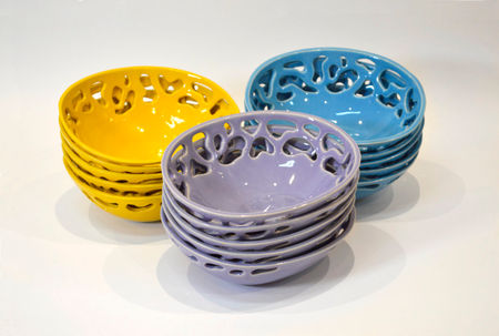 Tres pilas de cuencos calados esmaltados en amarillo, azul y lila sobre fondo blanco