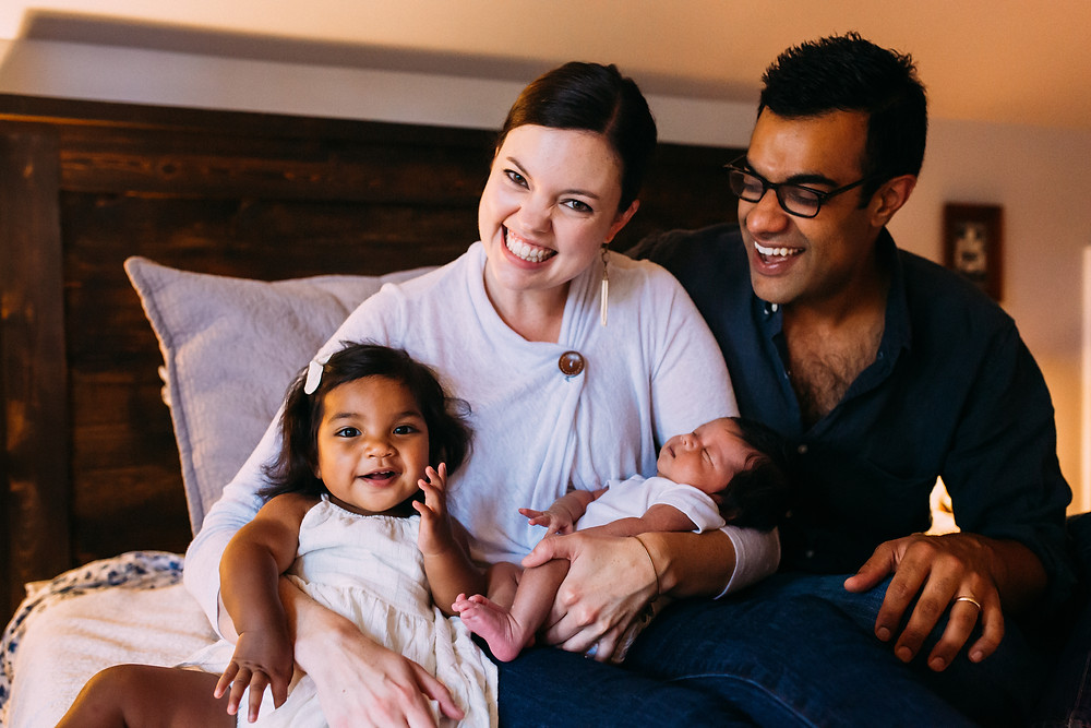 family with new baby on the bed