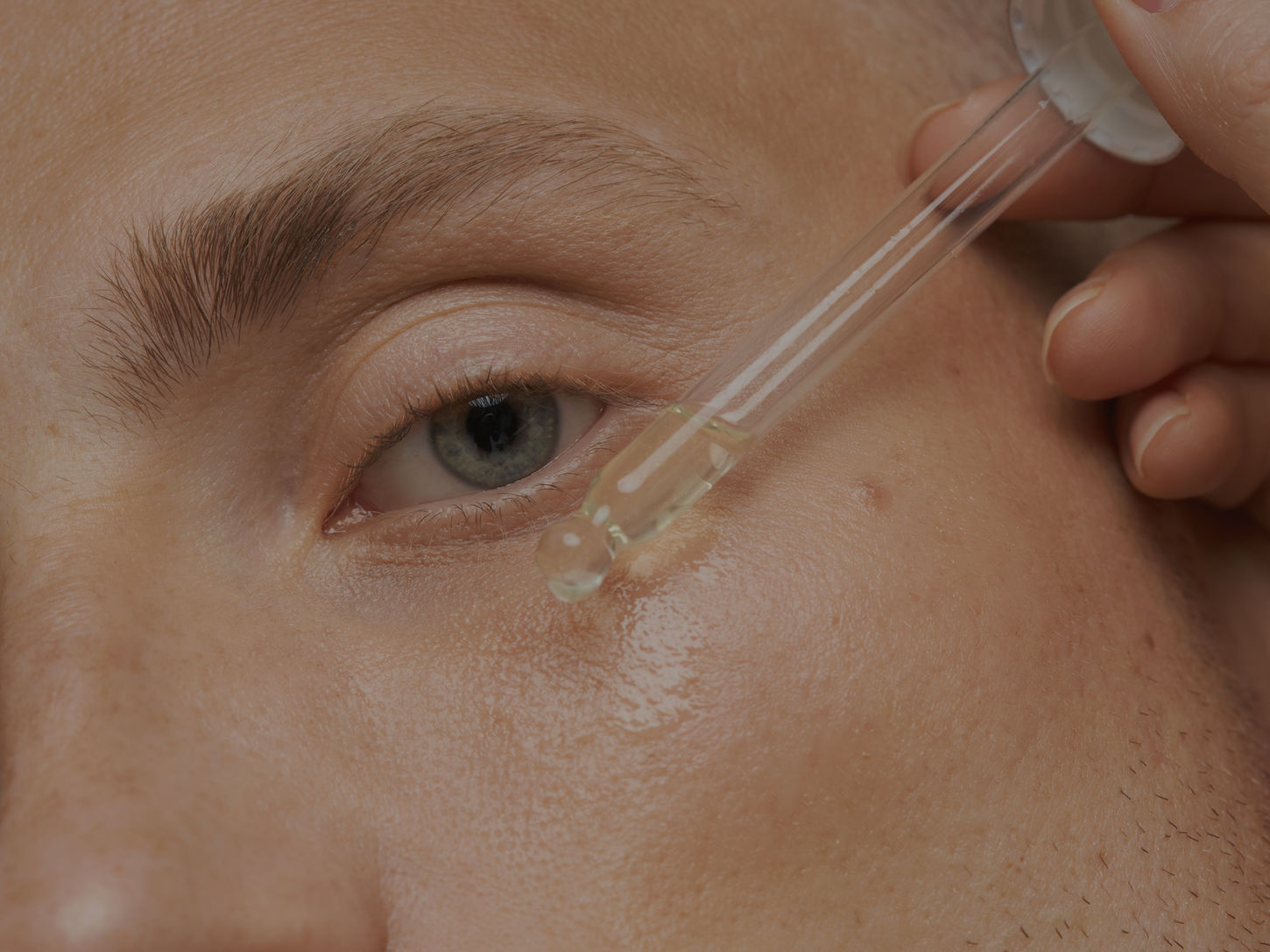 Applying skincare serum under the eye with a dropper
