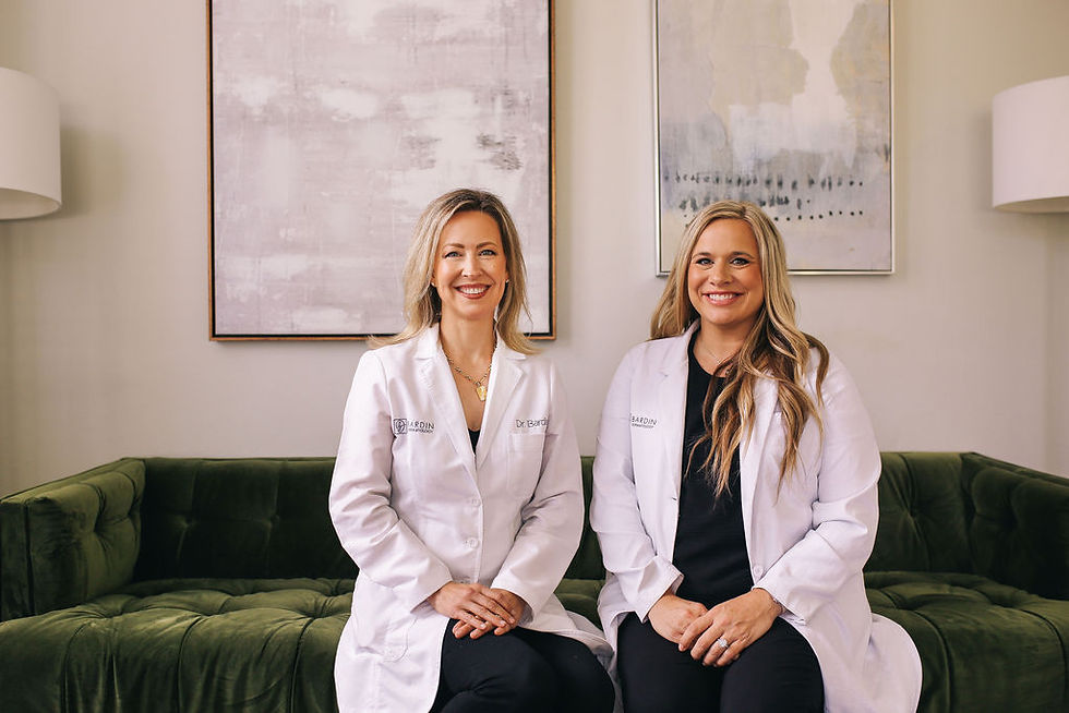 Two female doctors in white coats sitting on a green sofa.