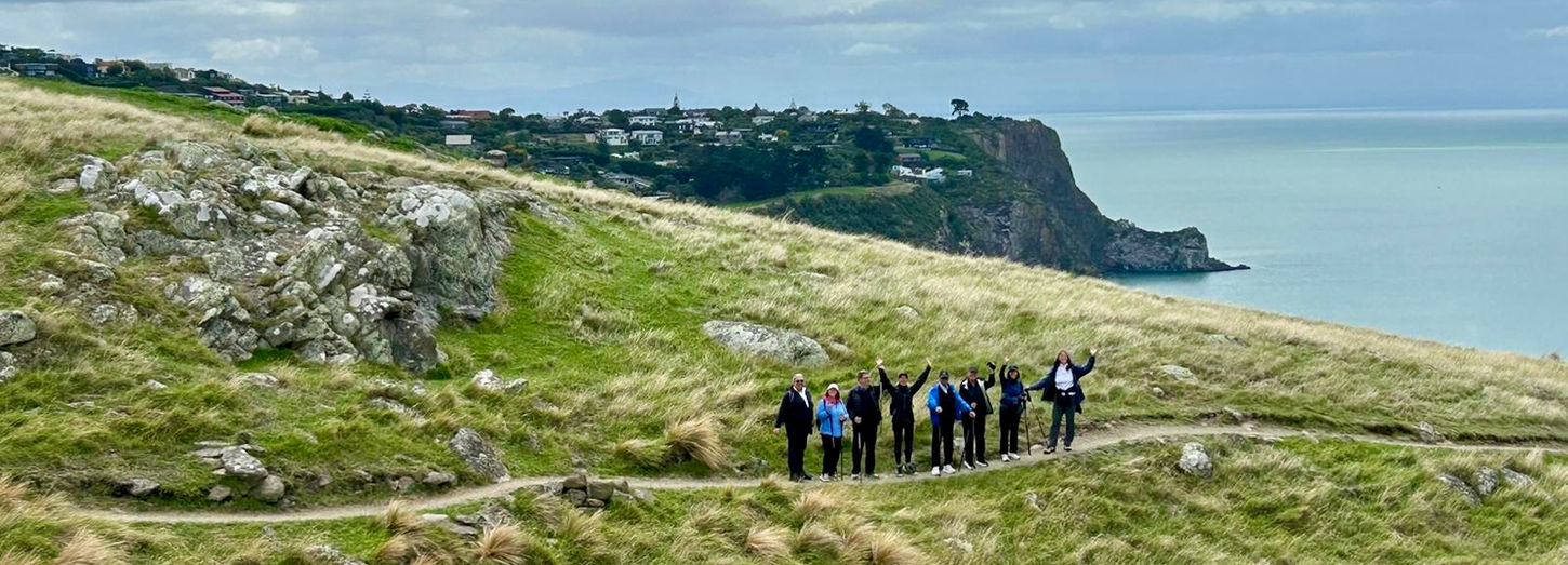 Friends stand and wave on the track during a shore excursion at Godley Head near Christchurch