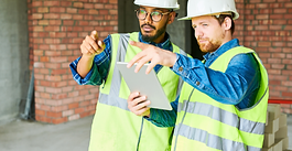 Construction professionals reviewing project information on a tablet inside a building under construction.
