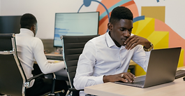 Professional working on a laptop at a desk in a modern office.