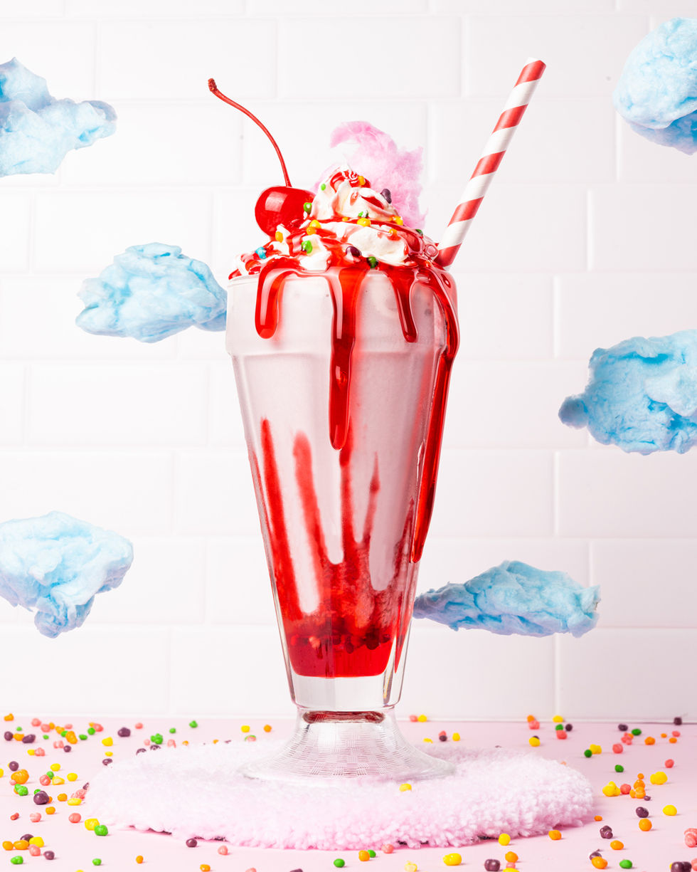 A miniature scene featuring a milkshake surrounded by cotton candy clouds, creating a whimsical and dreamy atmosphere.