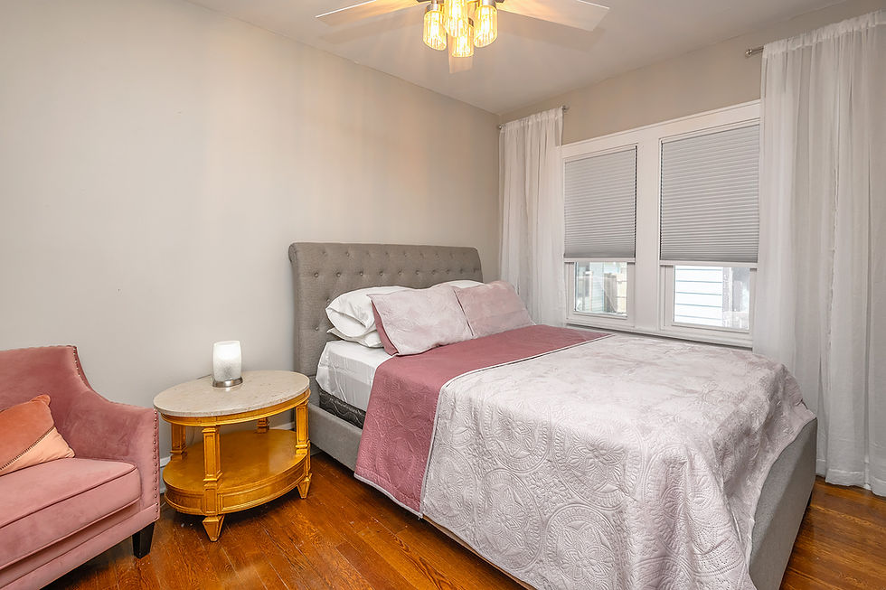 Bedroom with bed, nightstand, and pink armchair