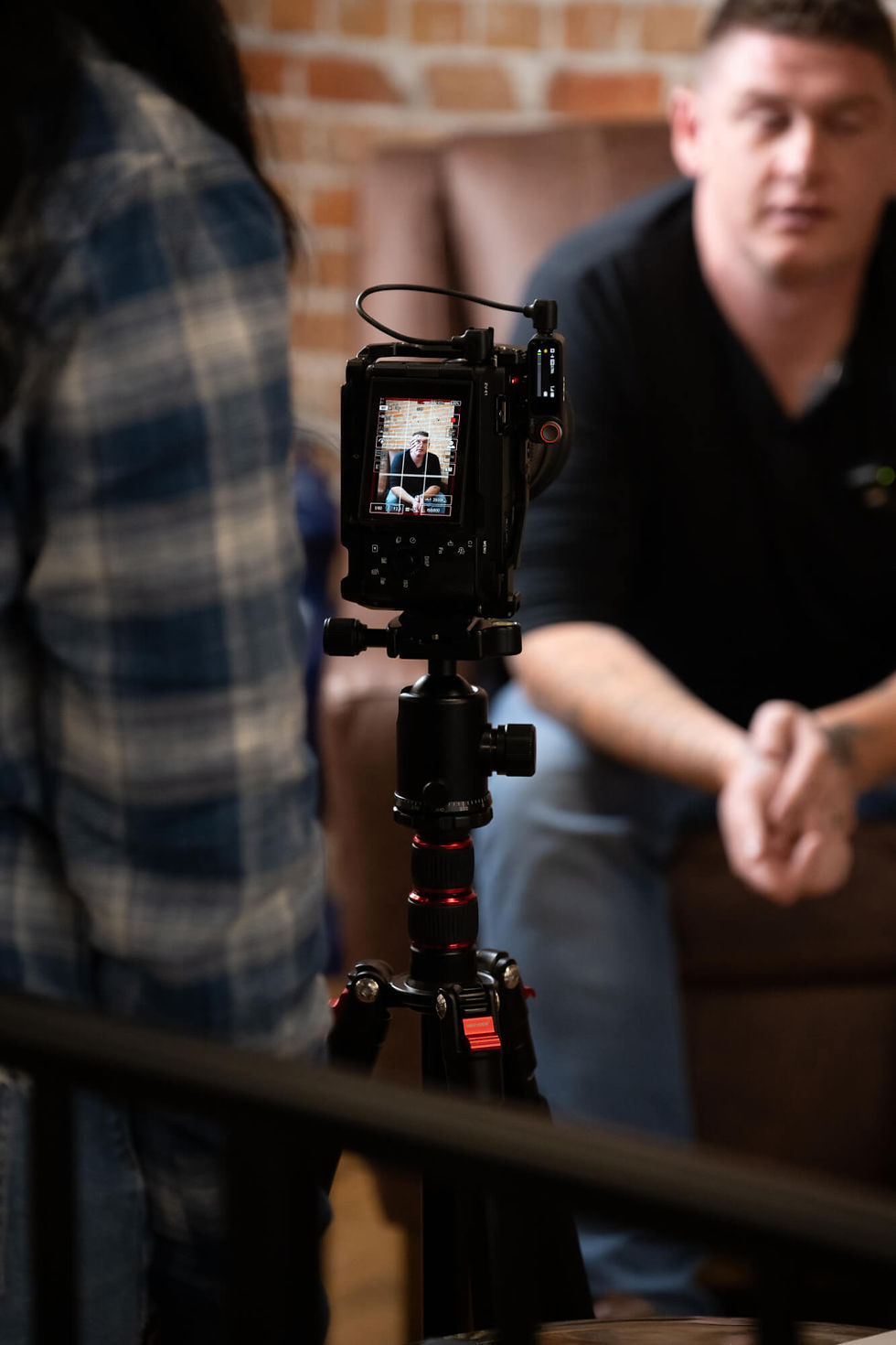 Over the shoulder view of a camera rig's display of a subject who is blurred out in the background