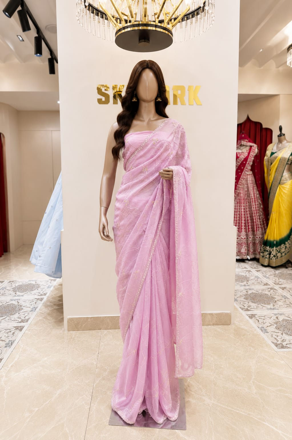 Pastel pink organza saree with delicate embroidered detailing, elegant border, lightweight sheer drape, and matching blouse