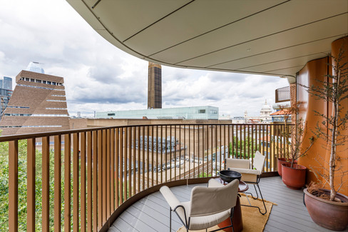 Covered balcony with curved railing, outdoor seating and urban skyline views