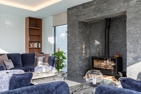 Modern sitting room with dark stone fireplace, bespoke shelving and soft contemporary furnishings