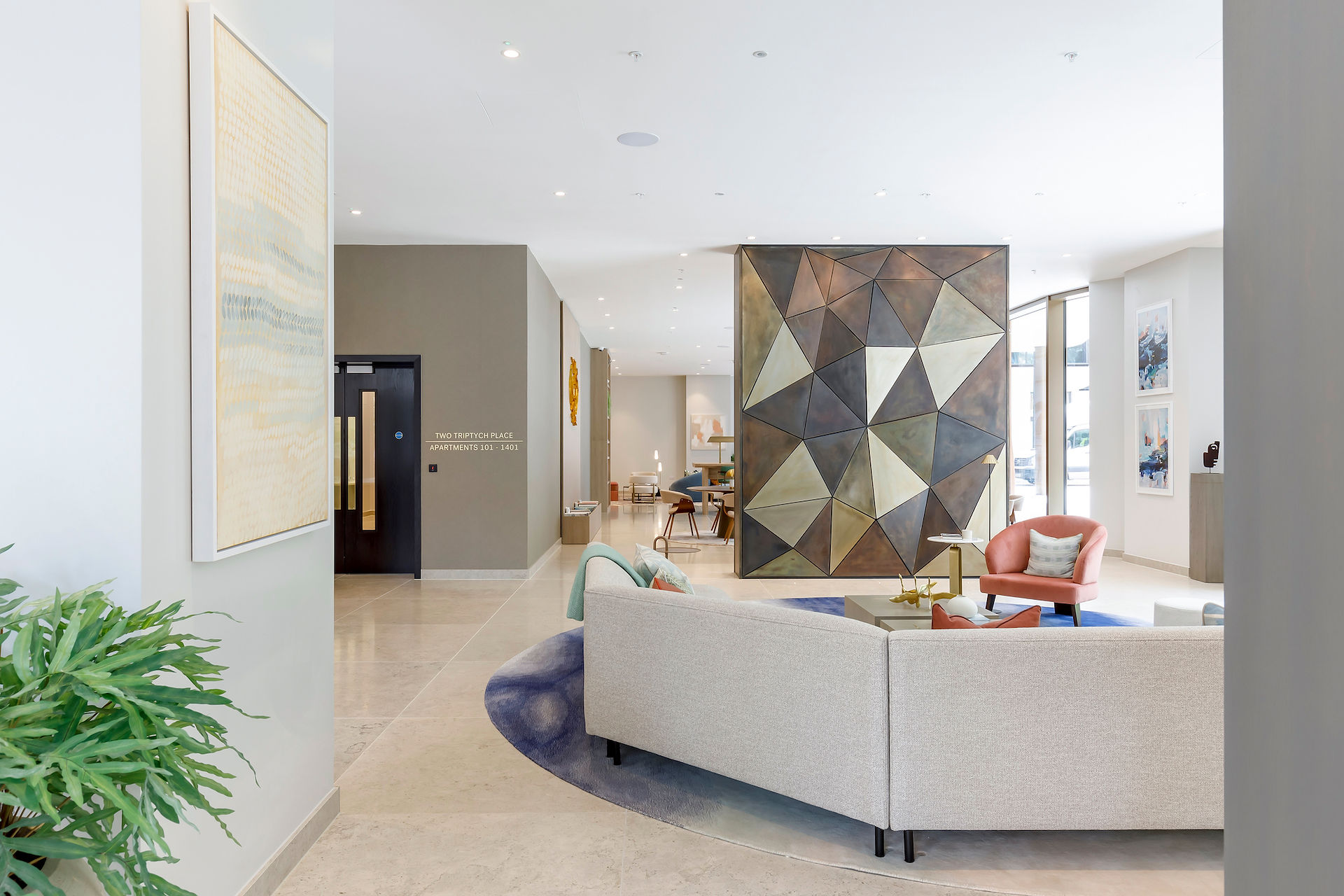 Contemporary reception lounge in a modern apartment building with designer seating, artwork and natural light