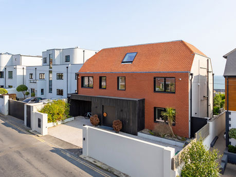 Modern detached house with walled front courtyard and gated parking, located on a residential street
