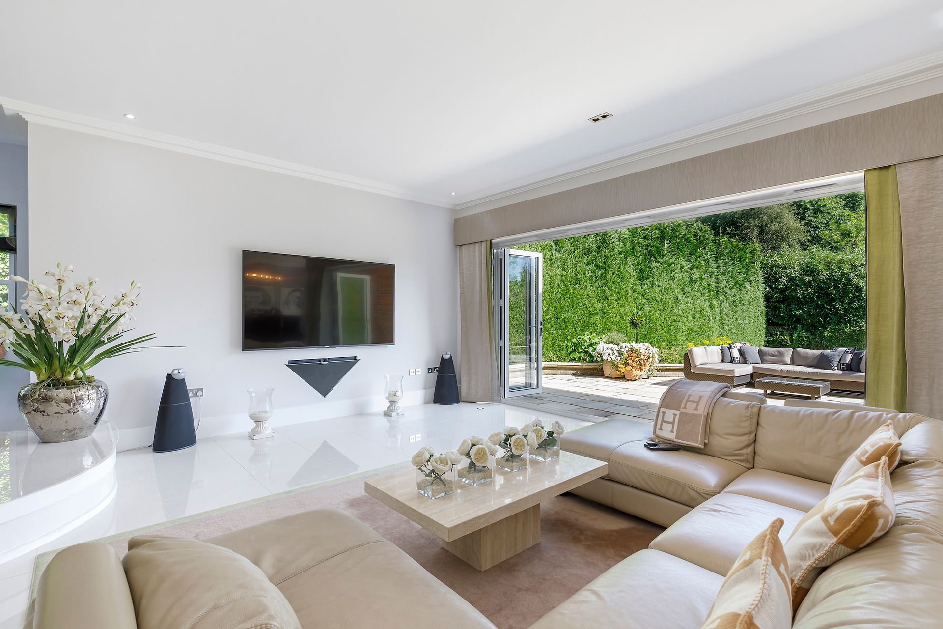 Luxury living room interior with neutral decor, garden views and direct access to outdoor seating area