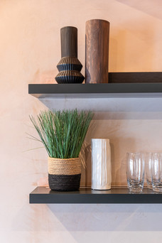 Close-up of styled kitchen shelving with decorative vases, plant and glassware in modern apartment interior