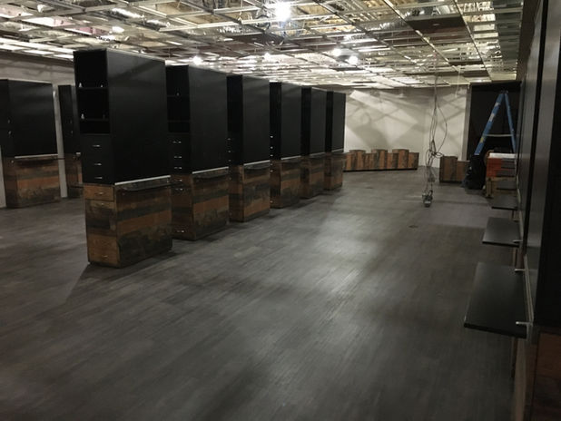 Industrial room with black divider walls, wooden bases, exposed ceiling.