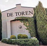 Eingang zum Weingut De Toren in Stellenbosch mit weißer Fassade und Zypressen.