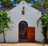 Weißes Weingutsgebäude von Diemersdal mit historischem Giebel und großem Holztor in Durbanville.
