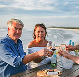 Gäste stoßen mit Weißwein an der Küste bei Blake Family Wines in Yzerfontein an.