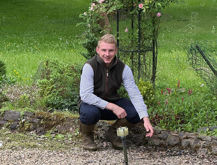 Photo of Rupert crouched in a garden in front of a pond