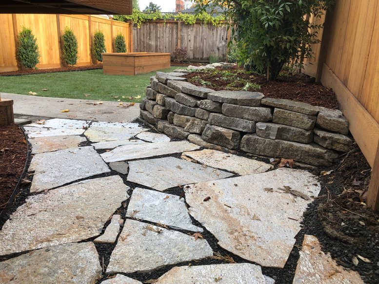 Full backyard landscape renovation featuring dry laid stone retaining wall, flagstone patio, new sod, raised garden bed, hedge installation, metal edging, new plantings, and mulching. Portland landscaping.
Vancouver landscaping. Landscape contractor. Retaining wall contractor.