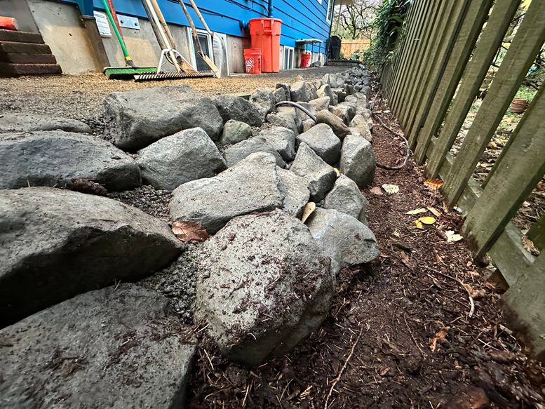 Rip rap style retaining wall using small basalt boulders to retain slope and provide pockets for planting into. 
Portland landscaping.
Vancouver landscaping. Landscape contractor. Retaining wall contractor.