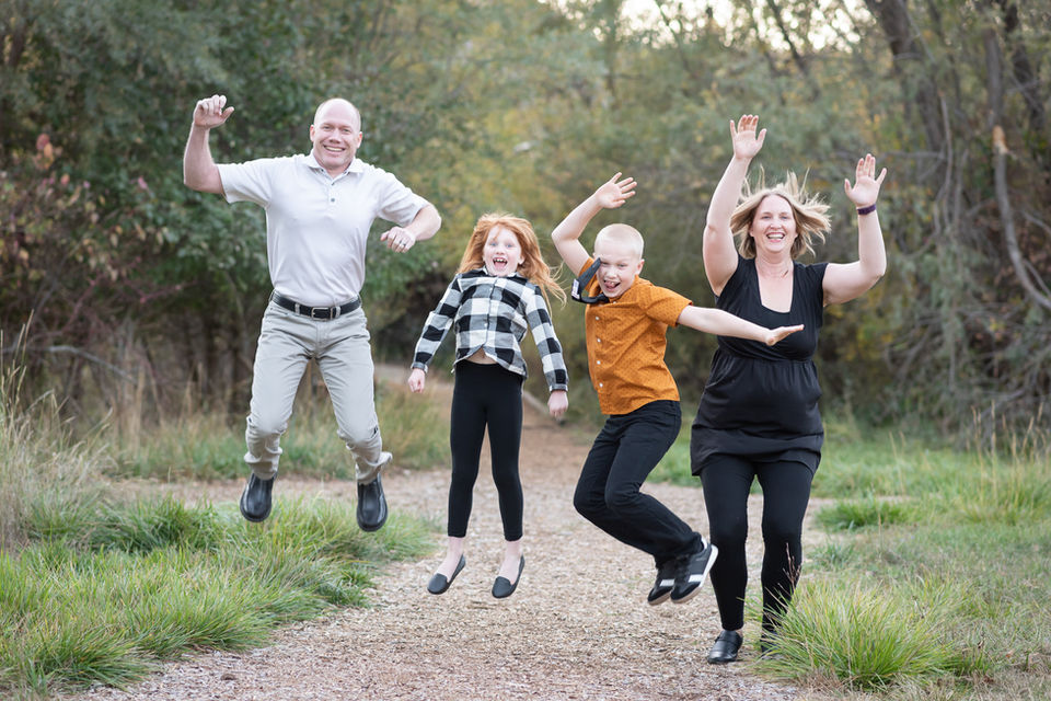 A family of four jumping and laughing while they have their photo taken at North Mountain Park in Ashland
