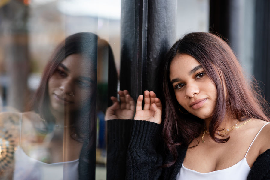 A high school senior posing against a window for her senior graduation session in downtown Ashland