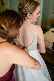 A bride having her dress zipped up.