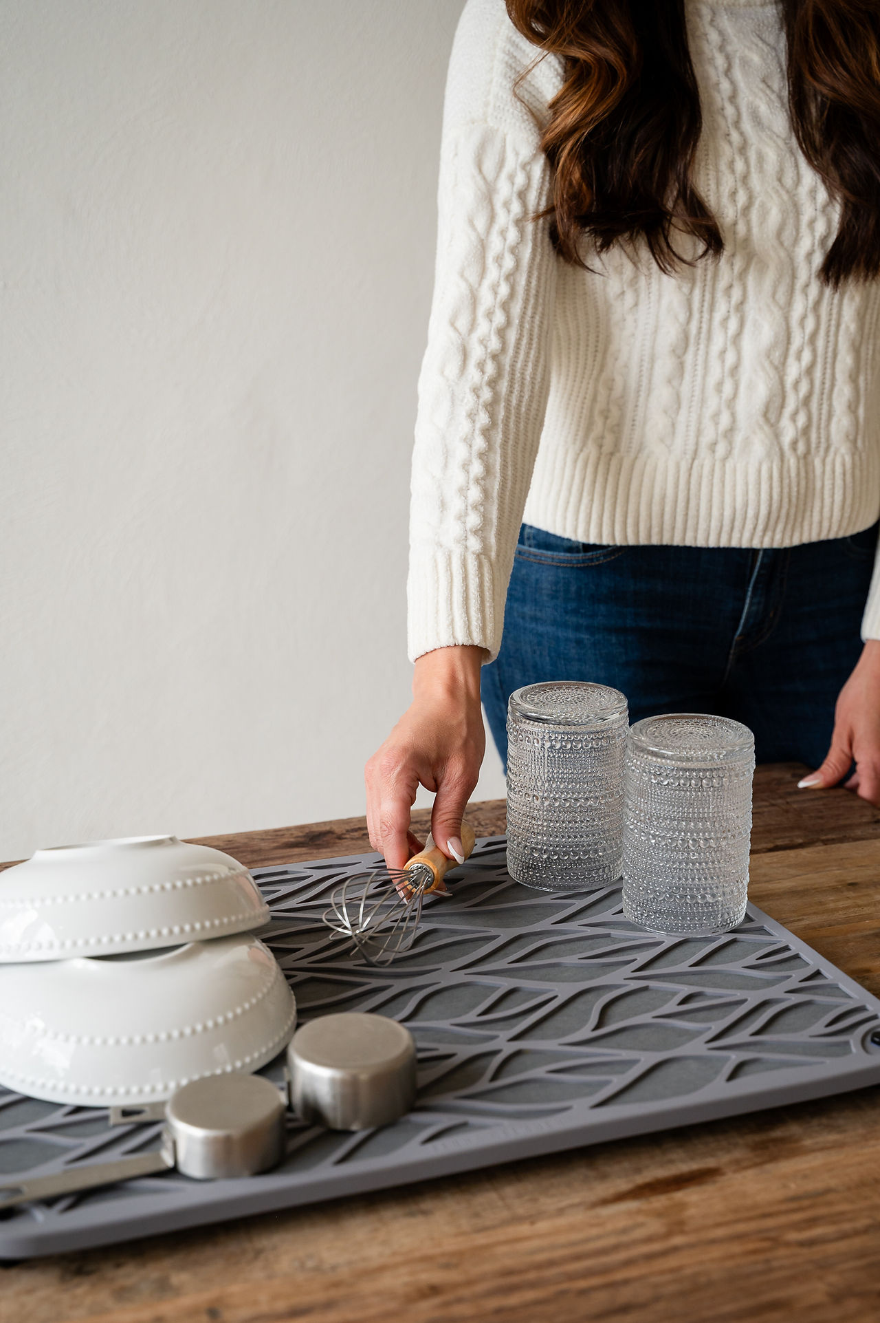 A hand reaching for silverware on a mat. 