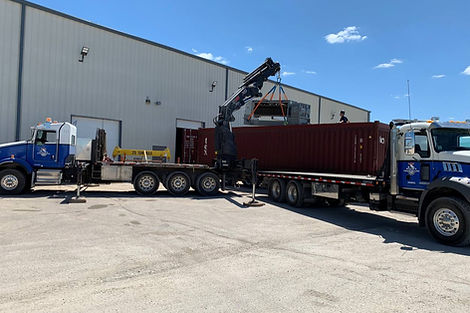 Crane truck assisting a cargo onto a transportation truck