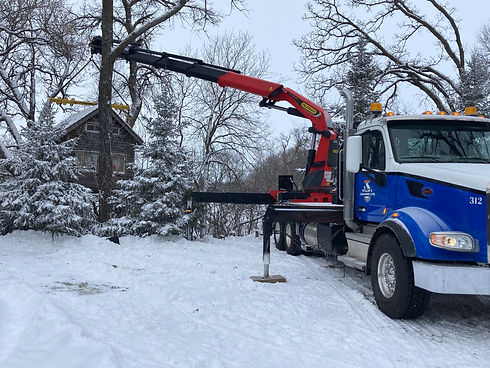 Crane truck offering services to a residential home covered in snow