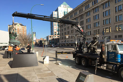 Crane truck assisting workers in installation of statue