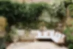 Outdoor area with sofa, small table with chairs and plants on the wall