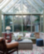 Conservatory with rug, wooden furtnirue, sofa and ottoman