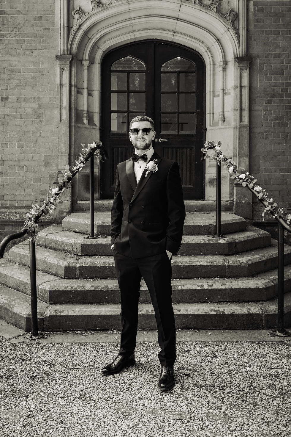 Man in suit standing on steps, wearing sunglasses.