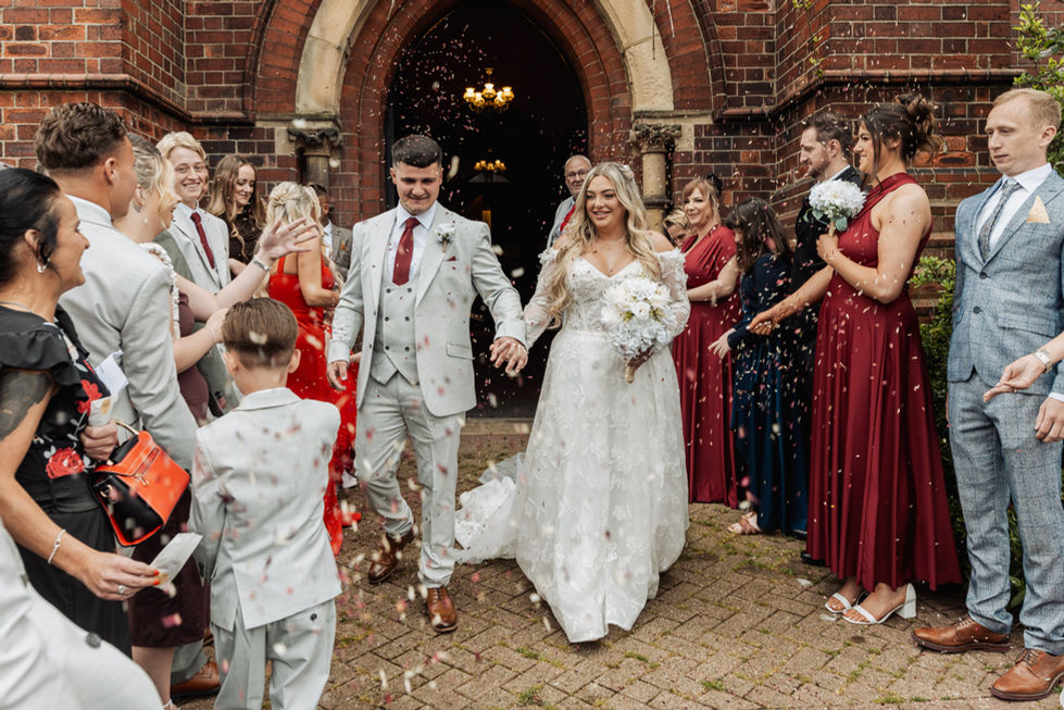 Bride and groom exiting church with guests celebrating.