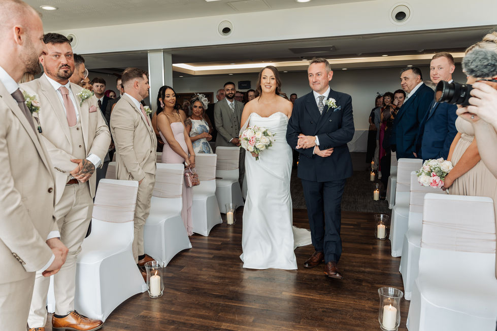 Bride walking down the aisle with guests watching.