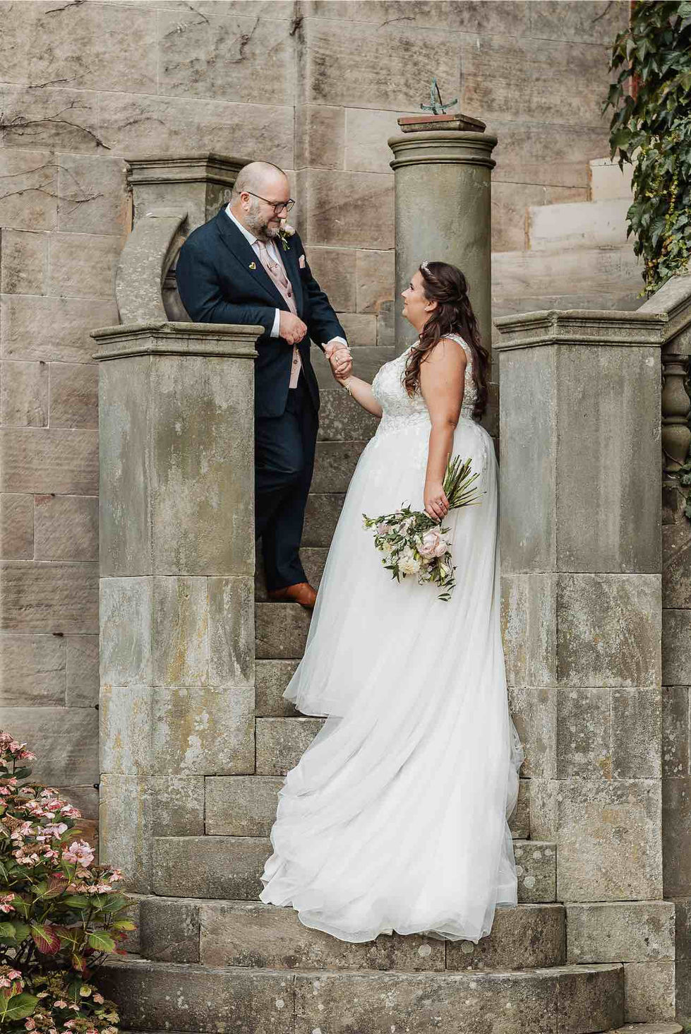 Bride and groom pose on stone steps.