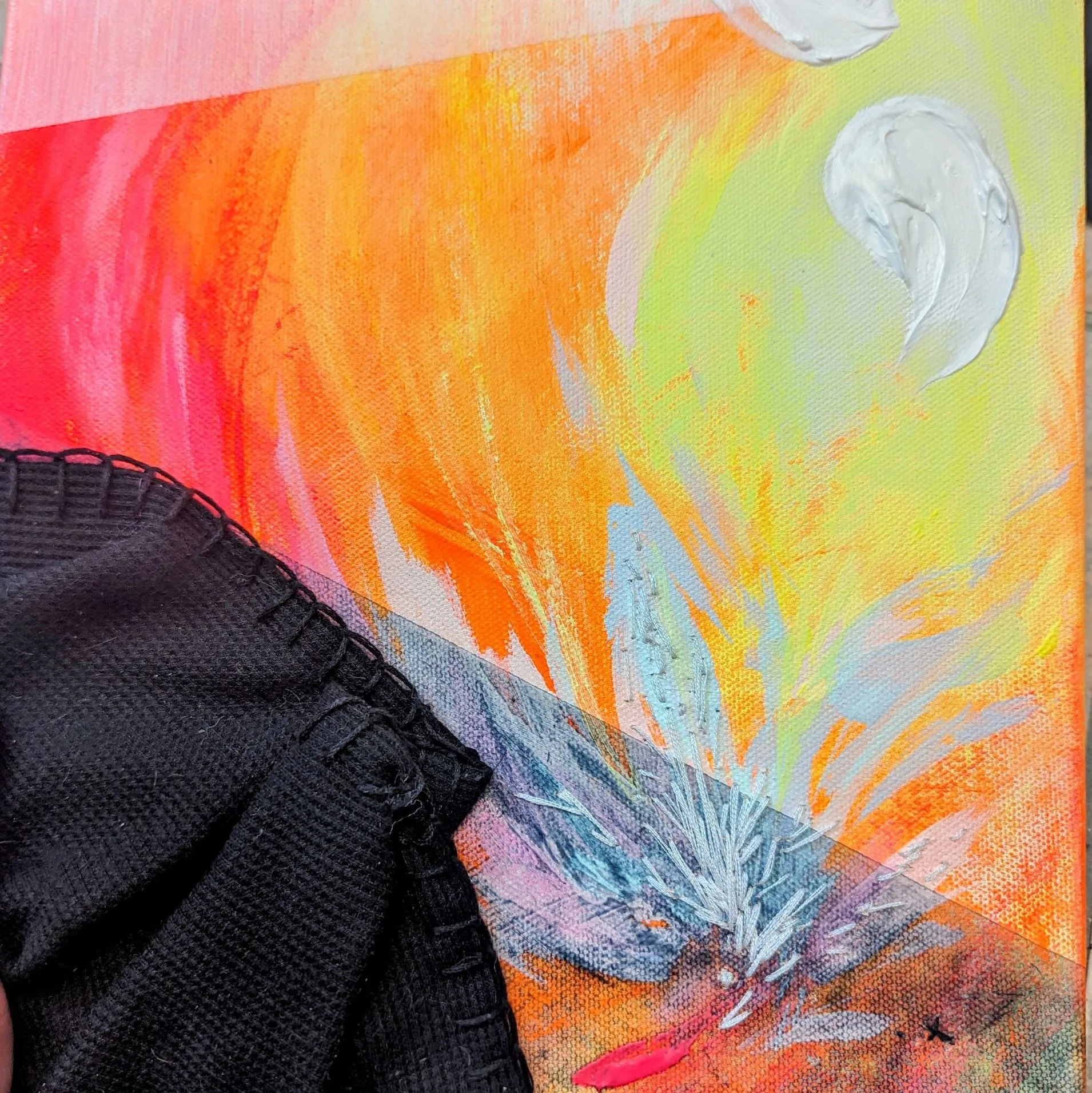 painting with bright strokes of orange red and white, at the corner lies a black piece of fabric