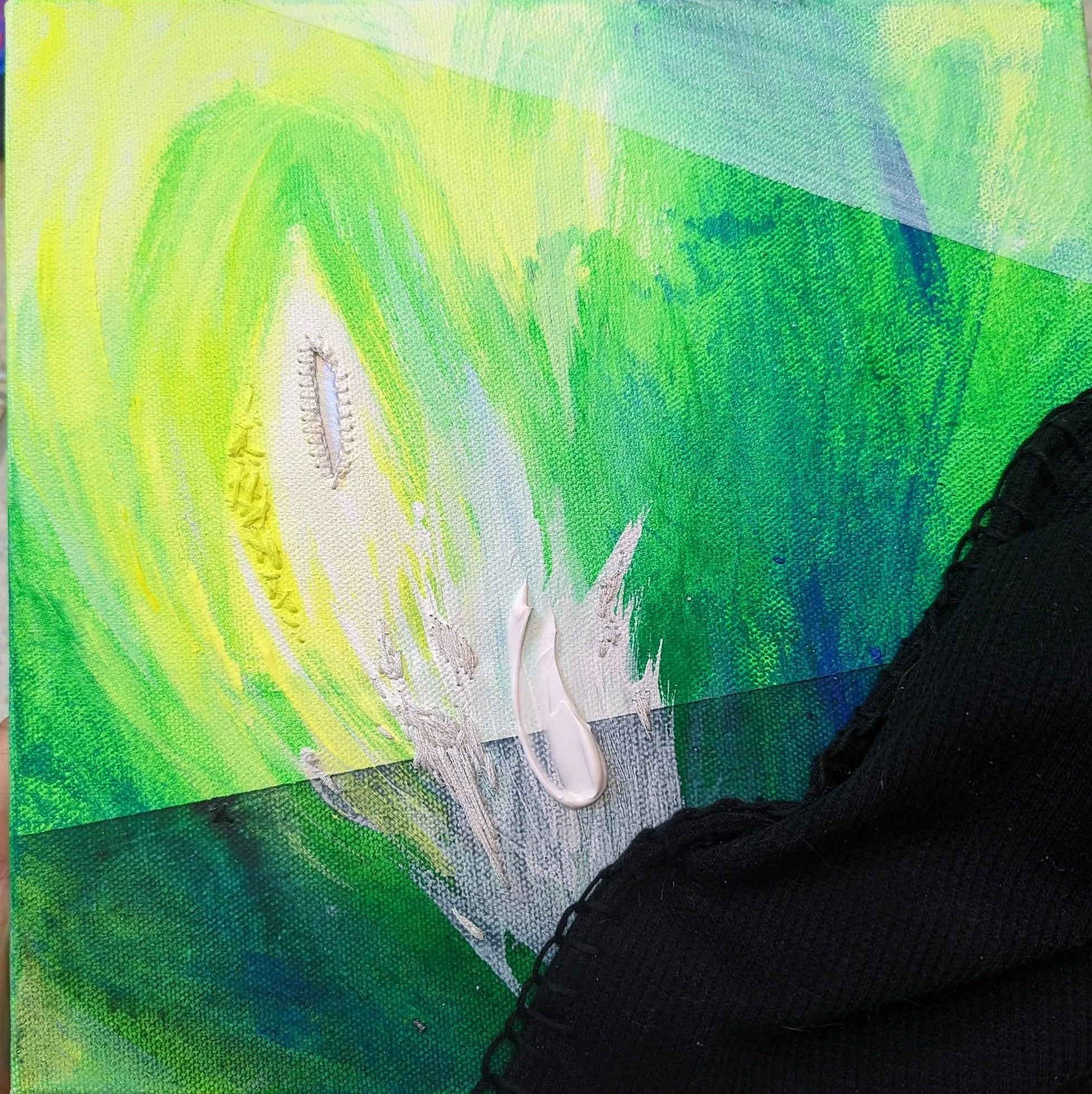 painting with bright strokes of green, blue and white, at the corner lies a black piece of fabric