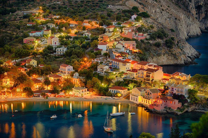 Assos village in Kefalonia at sunset with warm light over the harbor and waterfront houses