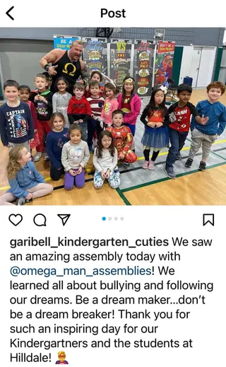 Omegaman poses with a kindergarten class after a school assembly on bullying prevention and making positive choices.