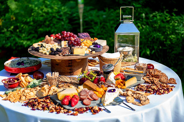 A charcuterie table with meats, cheeses, fruit, decorative baskets, and lanterns.