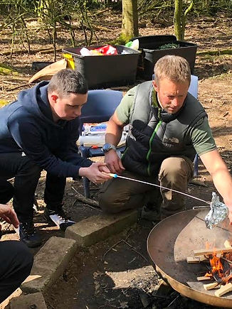 Two men cooking on a camp fire