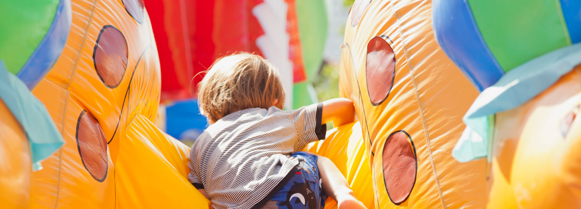 A child climbing over an obstacle in a blow up bouncy house. 