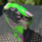 Spooky purple, green, and black Witches Curse Soap with a green withes finger on top.