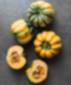 Thumbnail: Several Carnival squash on a counter with one sliced in half, exposing the seed cavity inside.
