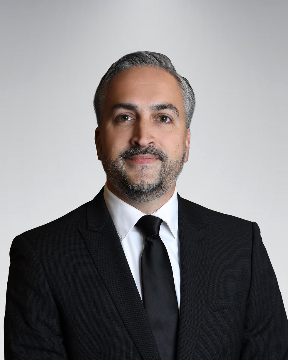Michael Zile sits facing forward in black suit and tie