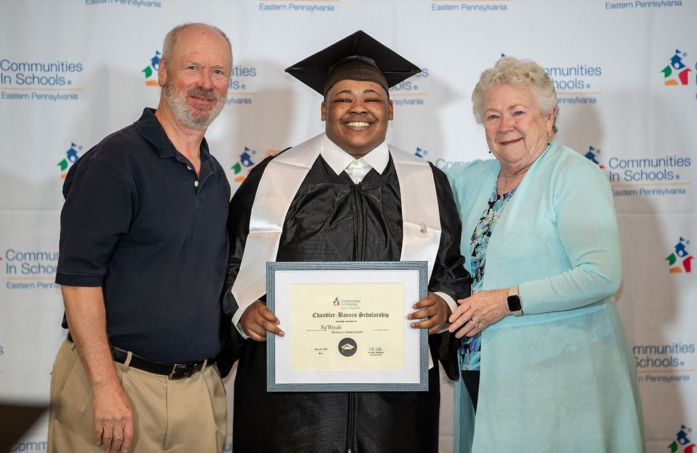 elder man and woman stand with young man holding diploma