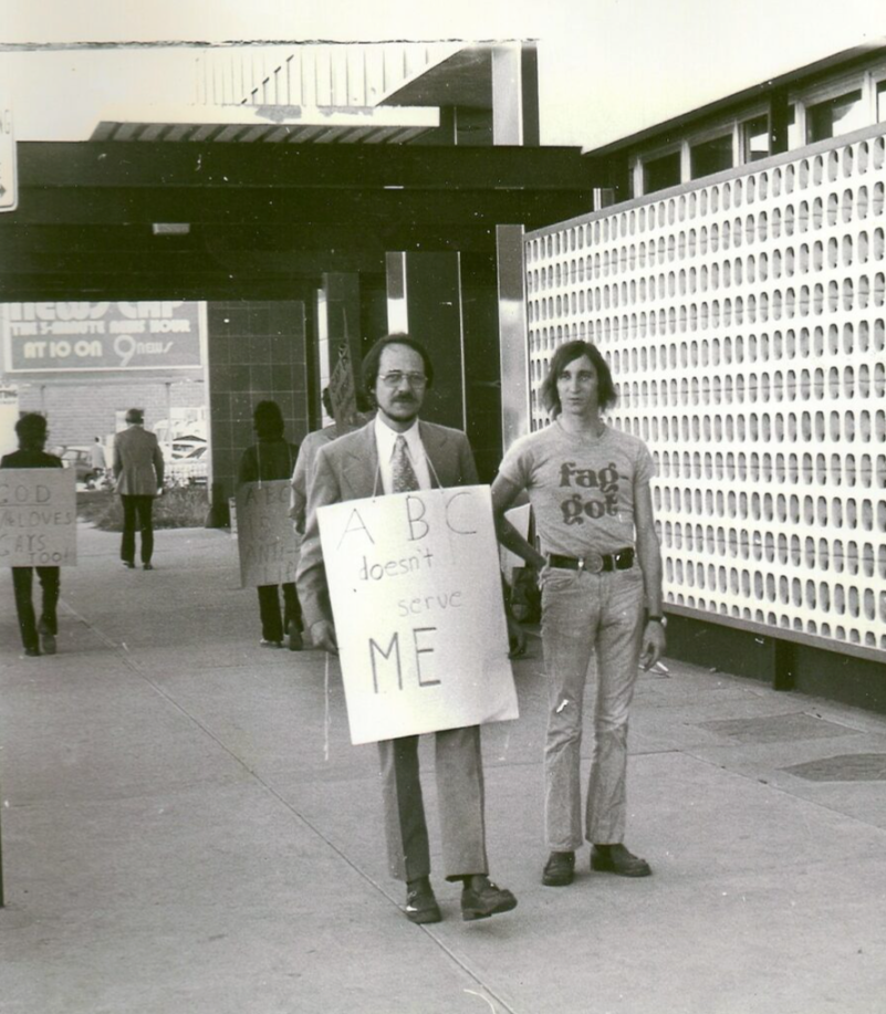 Gerald Gerash (left) and Lynn Tamlin (right) representing the Gay Coalition of Denver picket an anti-gay movie at Denver TV Channel by unknown, 1974. Center on Colfax.